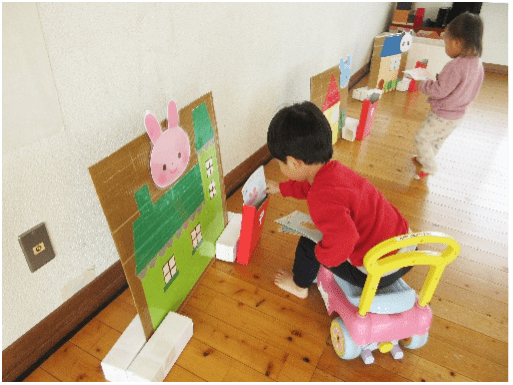 カートに乗って郵便屋さんごっこをして遊ぶ園児