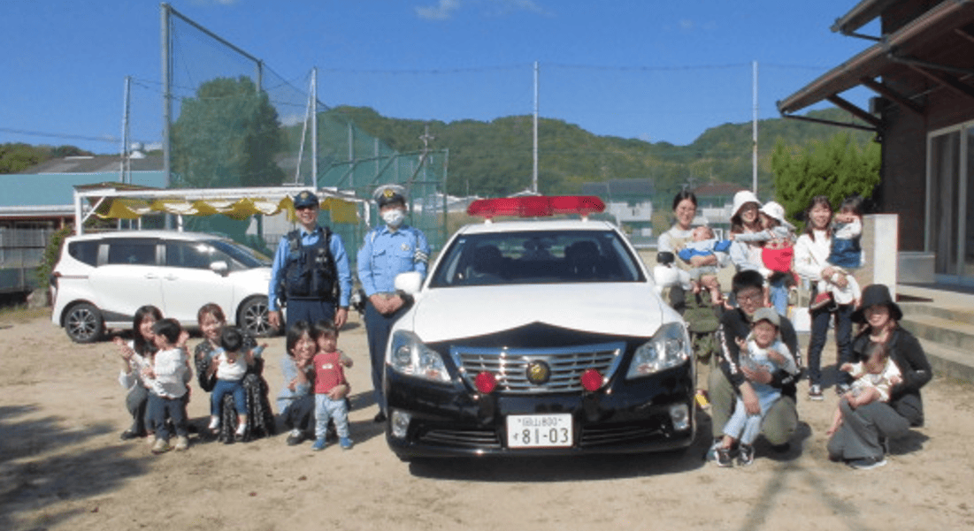 交通安全教室に参加した親子、警察、パトカーの集合写真