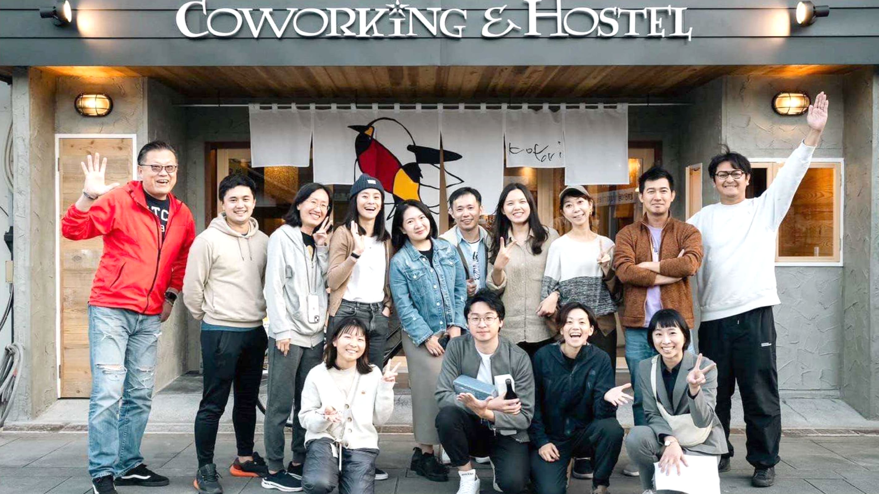 コワーキング＆ホステルの前で大勢の人が記念写真を撮っている様子