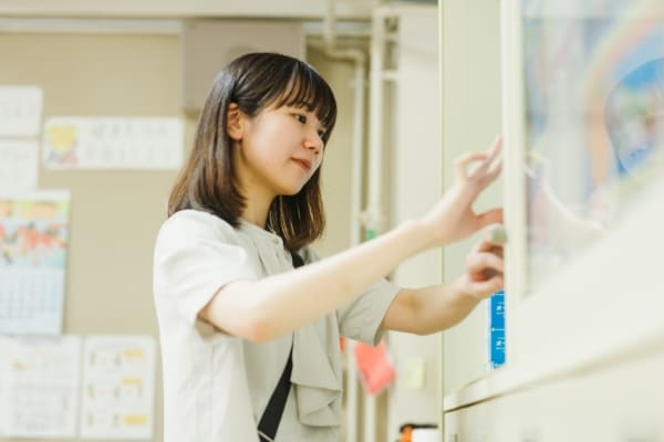 ホワイトボードにポスターを張っている先生の写真