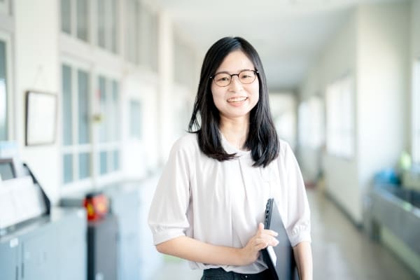 廊下でほほ笑む学校事務の写真